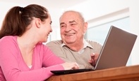 Señor mayor junto a una chica jóven aprendiendo a utilizar el ordenador.